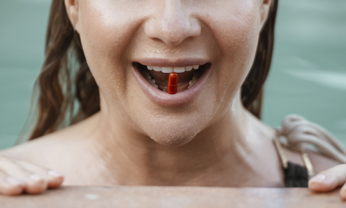 Mulher a tomar uma cápsula de nutricosmética como parte da sua rotina de beleza de dentro para fora