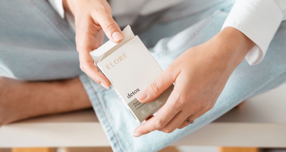 Mulher a segurar a embalagem de Éloré Detox, suplemento de nutricosmética com alcachofra e chá de java