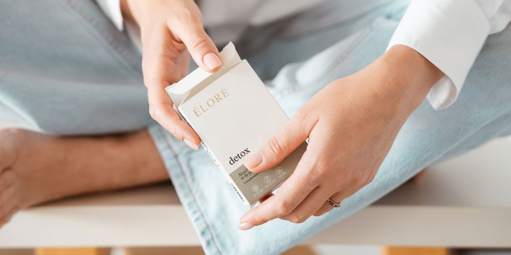 Mujer sosteniendo el packaging de Éloré Detox, complemento de nutricosmética con alcachofa y té de java